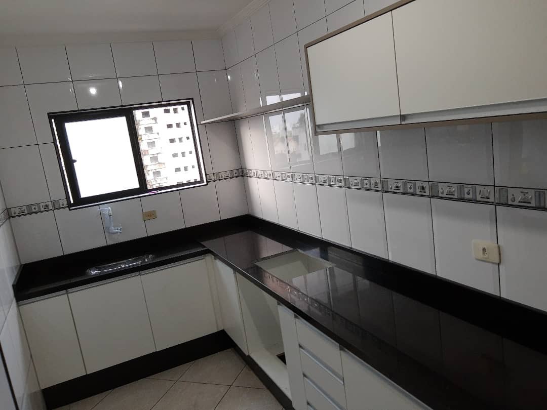 Cozinha planejada com bancada preta em granito e armários brancos
